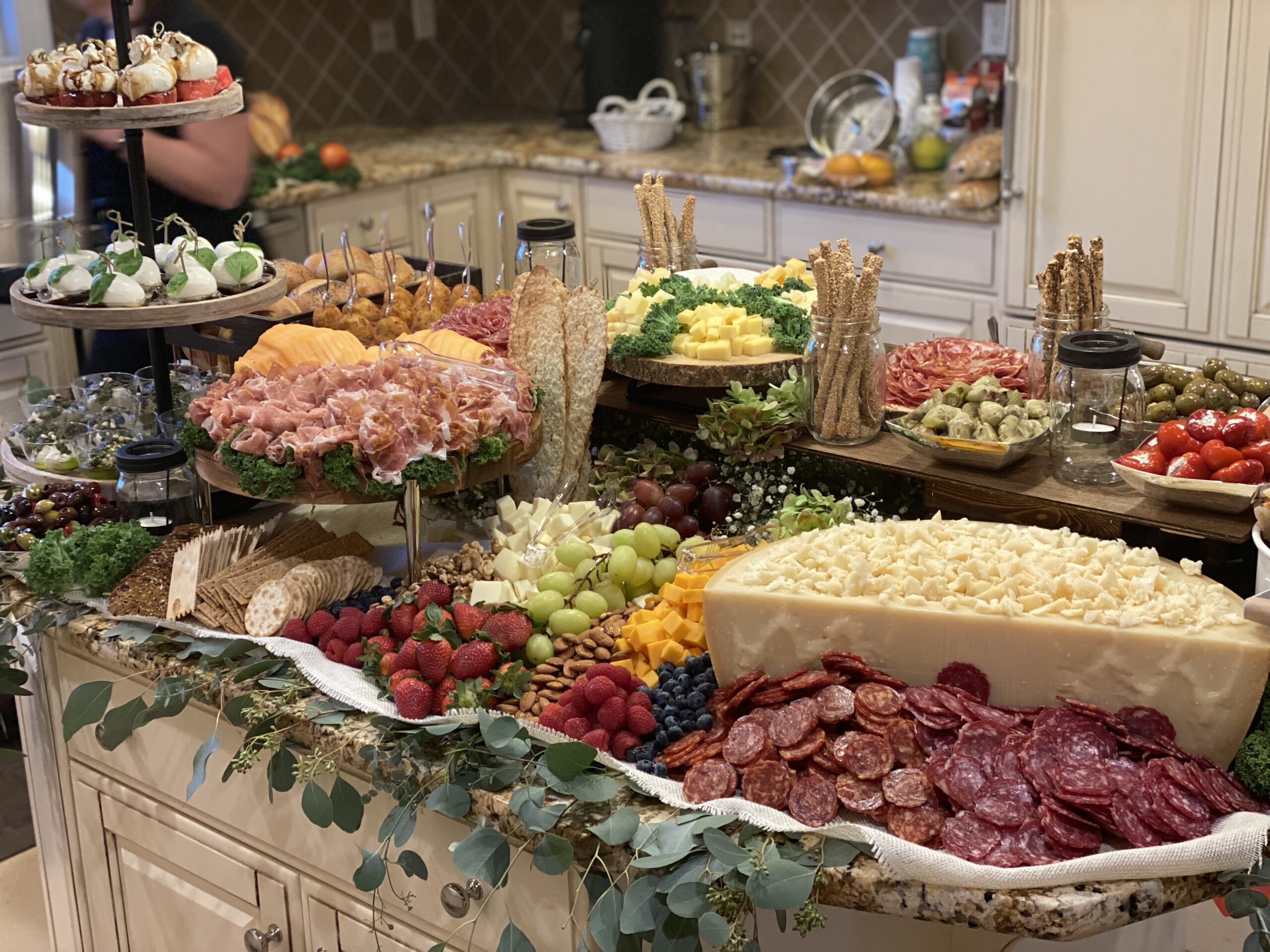 Beautiful meat, cheese, fruit, and bread spread arranged on a kitchen island