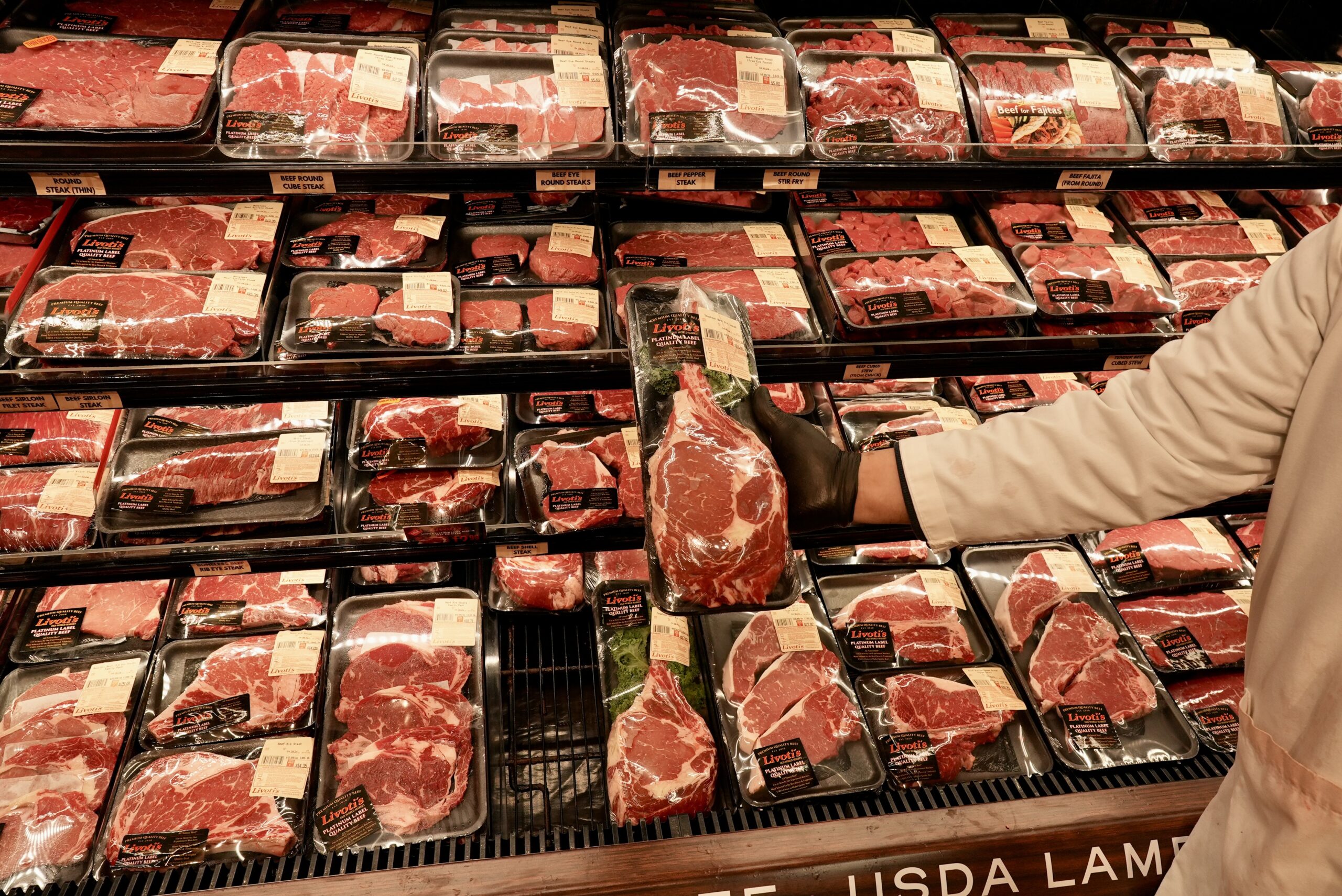 Butcher showing various meats for sale at Livoti's Old World Market